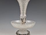 a silver vase on a stand on a gray background