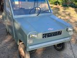 un petit camion vert garé dans l'allée
