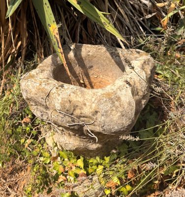 une jardinière en pierre posée au milieu de la pelouse