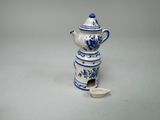 une petite théière bleue et blanche contenant une cuillère