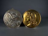 two gold and silver medallions of a man and a woman