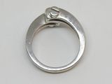 une bague en argent sertie d'un diamant, posée sur une table