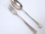 two spoons and a fork on a white table