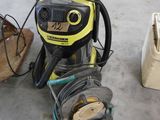 un aspirateur jaune et noir dans un garage, à côté d'autres outils