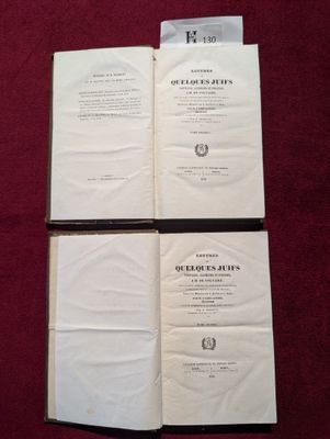 deux livres ouverts posés sur une table recouverte d'un tissu rouge