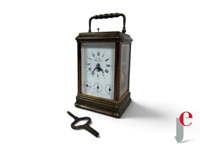 une petite horloge avec une clé à côté, posée sur une surface blanche