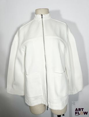 une veste blanche posée sur un mannequin, devant un fond blanc