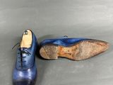 pair of blue leather shoes with laces on a grey surface