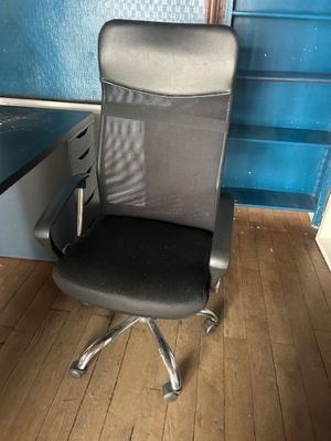 a black office chair sitting in front of a blue wall