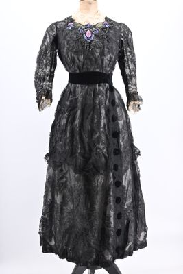 a black dress on a mannequin stand with a white background