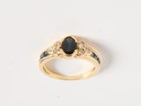 gros plan d'une bague en or avec un saphir et des diamants