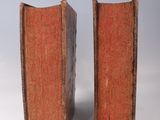 pair of old books sitting on top of each other on a white surface