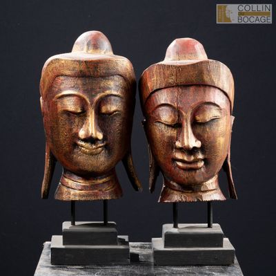 paire de têtes de Bouddha sculptées dans le bois, posées sur un socle en marbre