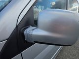 a side view mirror of a silver car on the side of the road