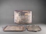 three silver trays sitting on a stand on a gray surface