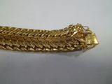 une image d'un bracelet en or sur une surface blanche