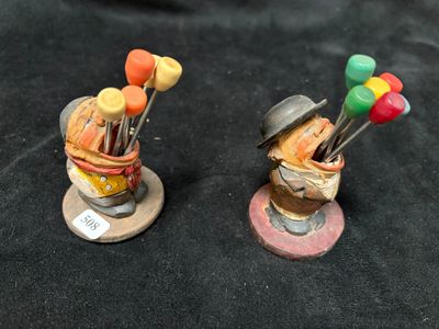 two figurines of a man with a hat and a bunch of pins