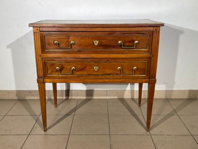 a small wooden chest of drawers on a tiled floor