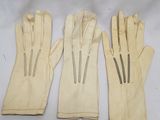 three pairs of white leather gloves sitting on top of a white table