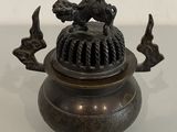 a small bronze pot with a bird on top