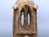 a wooden sculpture of a face on a glass stand