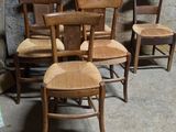 Plusieurs chaises en bois sont alignées contre un mur dans une pièce.