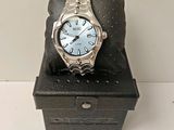 une montre en argent posée sur un coffret noir