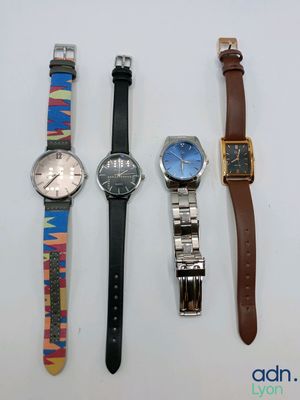 quatre montres différentes sont alignées sur une surface blanche