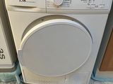 une machine à laver blanche posée sur un sèche-linge