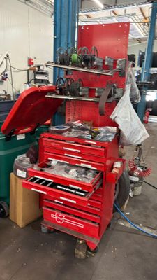 une boîte à outils rouge posée à côté d'une poubelle verte dans un garage