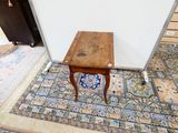 une petite table en bois avec un carreau bleu et blanc posé par terre