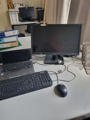 un ordinateur portable posé sur un bureau, à côté d'un écran et d'un clavier