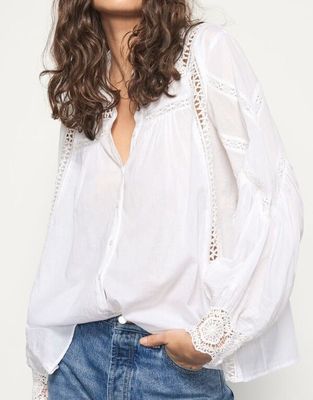 a woman wearing a white blouse and jeans posing for a picture