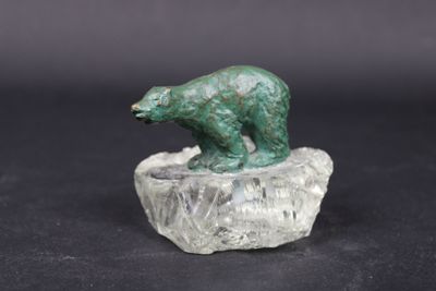 statue d'un ours vert posé sur un rocher, sur fond noir
