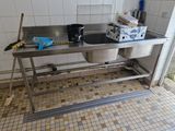 une cuisine équipée d'un évier et d'une poubelle posée sur le plan de travail