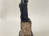 une image représentant une statue d'une femme assise sur un bloc de pierre