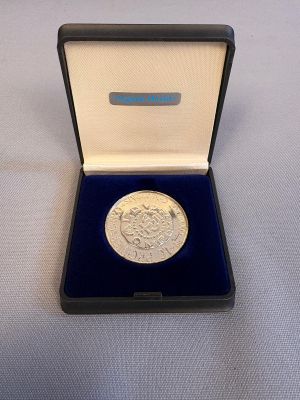 une pièce d'argent dans une boîte bleue posée sur une surface blanche