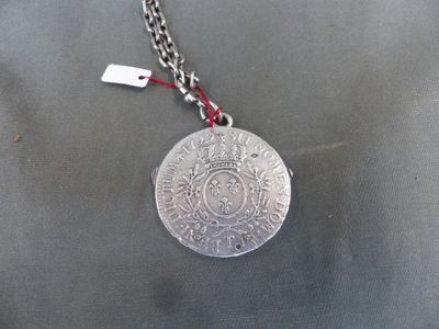 a silver coin on a chain with a red cord