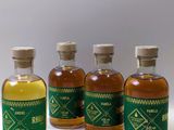 quatre petites bouteilles d'alcool sont alignées sur une surface blanche
