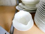 a stack of white plates and bowls on a shelf