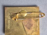 a gold pin with a pair of scissors on it