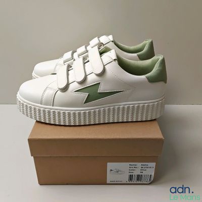 a close up of a pair of white and green sneakers on a box