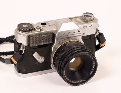 a silver camera with a black strap and a white background