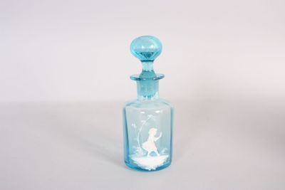 une petite bouteille en verre bleue sur laquelle est représentée une femme