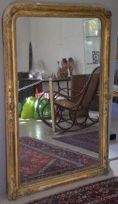 a large mirror in the middle of a room with a rocking chair in it