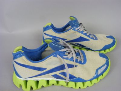 a pair of white and blue running shoes with green soles