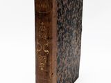 un vieux livre posé sur une table sur une surface blanche