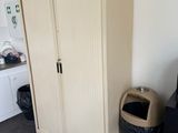 a cabinet in the corner of a room with a trash can