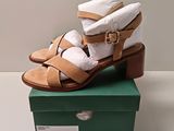 pair of women ' s tan sandals on a green box on a white surface