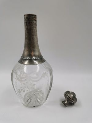 une bouteille en verre ancienne, munie d'un couvercle en argent et d'un petit bouchon en métal